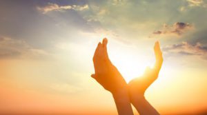 hands holding the sun at dawn